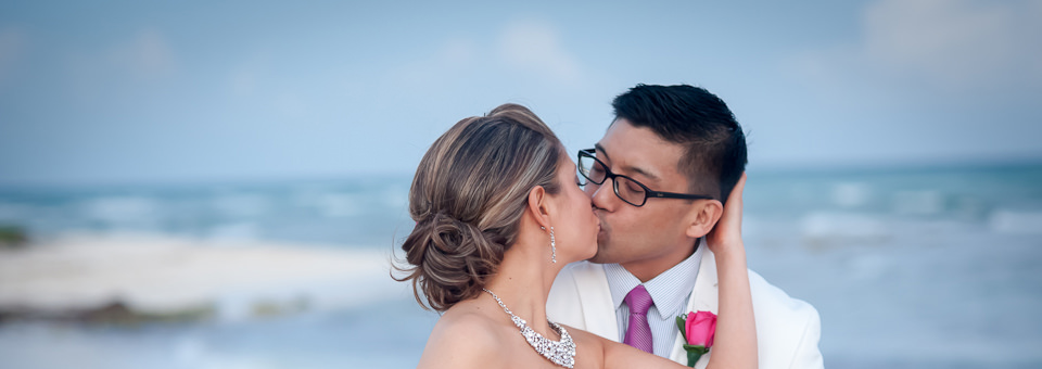 bride and groom kiss against backdrop of the sea, photographed by Cancun wedding photographer, dorota jamal